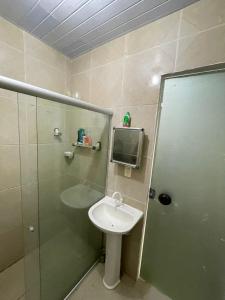 ein Bad mit einem Waschbecken und einer Dusche sowie einen TV in der Unterkunft claussporto in Porto De Galinhas
