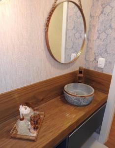 eine Holztheke mit einem Spiegel und einer Schüssel darauf in der Unterkunft Apartamento novo centro de Canela in Canela