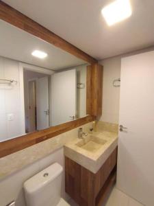 ein Badezimmer mit einem Waschbecken, einem WC und einem Spiegel in der Unterkunft Apartamento novo centro de Canela in Canela