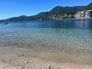 a body of water with a rocky beach and mountains at Canottieri home in Omegna