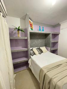 Schlafzimmer mit einem Bett mit lila Regalen in der Unterkunft claussporto in Porto De Galinhas