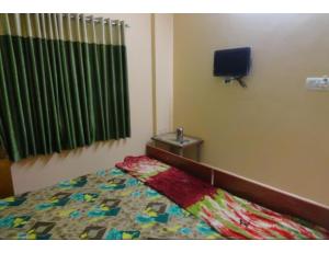 Hotel Shree, Somnath في سومناث: غرفة نوم بسرير وتلفزيون في غرفة