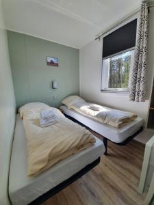 two beds in a room with a window at Ferienpark Auf dem Simpel - Heide-Lodge 3 in Soltau