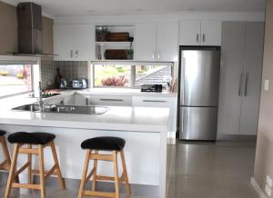 cocina con armarios blancos y nevera de acero inoxidable en Sunny Modern 3 Bedroom Townhouse, en Newnham