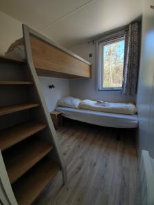 Cette petite chambre comprend des lits superposés et une fenêtre. dans l'établissement Ferienpark Auf dem Simpel - Heide-Lodge 1, à Soltau