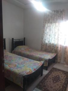 een slaapkamer met 2 bedden, een raam en een tapijt bij Fes in Fès
