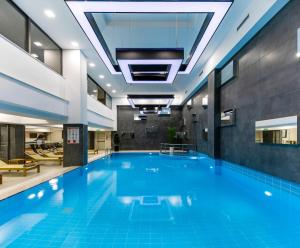 a large swimming pool in a building with blue water at Anemon Diyarbakır Hotel in Kayapınar