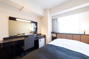 a bedroom with a bed and a desk and a mirror at APA Hotel TKP Nippori Ekimae in Tokyo