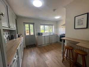 a large kitchen with white cabinets and wooden floors at Cameo Cottage 