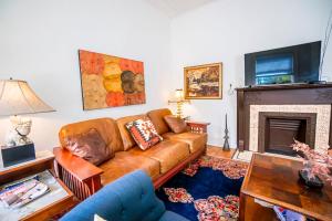 sala de estar con sofá de cuero marrón y chimenea en Step Back in Time Charming Victorian with Modern Amenities en Homestead