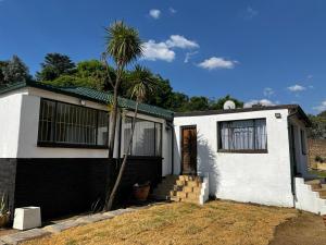 uma casa branca com uma palmeira em frente em BDN Backpackers em Joanesburgo