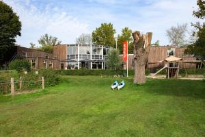 Dois pinguins estão sentados na relva em frente a um edifício. em Stayokay Hostel Dordrecht - Nationaal Park De Biesbosch em Dordrecht