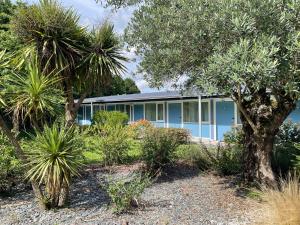 a blue house with palm trees in front of it at Hôtel Restaurant Bel Air Crevin - Axe Rennes Nantes in Crévin