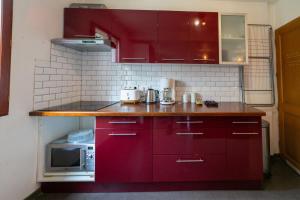 uma cozinha com armários vermelhos e um micro-ondas em Milly's House - Charming & Cosy em Milly-la-Forêt