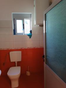 a bathroom with a toilet and a mirror and a window at FETAHU HOSTEL in Poliçan