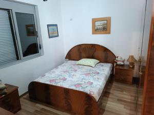 a bedroom with a bed with a wooden head board at FETAHU HOSTEL in Poliçan