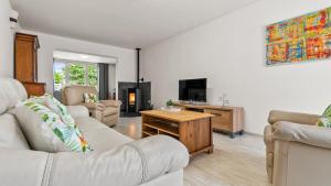 a living room with white couches and a tv at An's Vakantiehuisje in Dessel