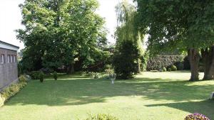 un jardin avec des arbres et de la pelouse ainsi qu'un bâtiment dans l'établissement Ferienwohnungen Meyerhof_ 55116, à Filsum