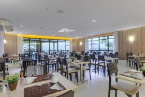 a dining room with tables and chairs and windows at Iate Plaza Flat 613 in Fortaleza