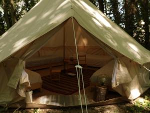 a canvas tent with a bed in the forest at Eco-Hostel Quinta das Relvas in Branca