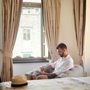 a man sitting in a window reading a book at King Kresimir Heritage Hotel in Šibenik
