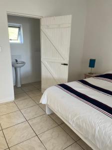 1 dormitorio con 1 cama y baño con lavamanos en Black Pearl Wine Cottage en Suider-Paarl