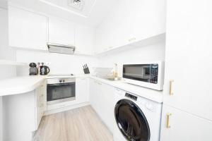 een witte keuken met een wasmachine bij Sky Gardens - Luxury Studio in Central DIFC in Dubai