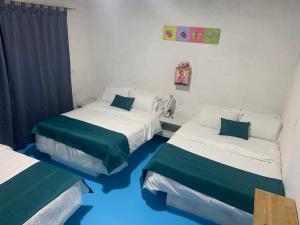 two beds in a room with blue floors at FINCA VILLA PEDREGAL RAQUIRA in Ráquira