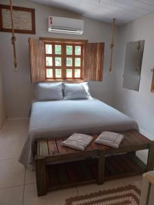 ein Schlafzimmer mit einem Bett und einem Tisch mit zwei Handtüchern in der Unterkunft Suítes Pirenópolis Piri in Pirenópolis