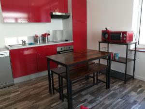 a kitchen with red cabinets and a wooden table at Cocoon Bugiste : travail, sport ou détente in Hauteville-Lompnes