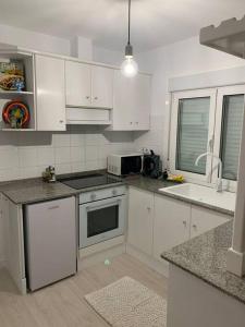 a kitchen with white cabinets and a sink and a microwave at Villa Simpatía in Merza