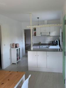 cocina con armarios blancos y mesa de madera en Villa Simpatía en Merza