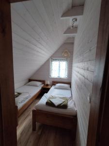 two beds in a small room with a window at Domki pod Kapeluszem nad jeziorem Patulskim,Kaszuby z opcją balii in Pierszczewo
