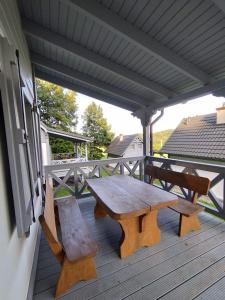 a wooden picnic table and a bench on a porch at Domki pod Kapeluszem nad jeziorem Patulskim,Kaszuby z opcją balii in Pierszczewko