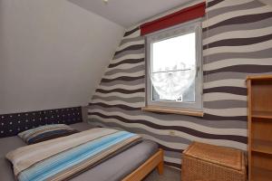 um quarto com uma parede listrada, uma cama e uma janela em Ferienhaus-Hellmich em Scheibe-Alsbach