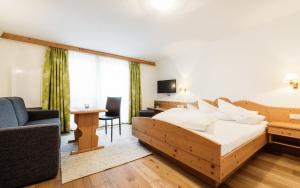 a bedroom with a bed and a couch and a tv at Hotel Regina in Serfaus