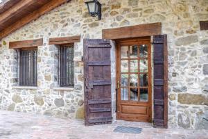 a stone building with a wooden door and windows at La Cabanya de la Rovira in Joanetes