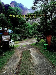 ブキティンギにあるTapian Ratu Campの多力間を読み取る標識のある未舗装道路
