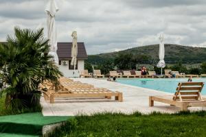 a swimming pool with wooden benches next to a building at Relax in Greci