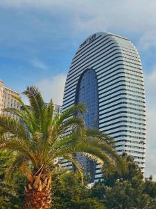 a tall building with a palm tree in front of it at Alliance Palace Batumi in Batumi