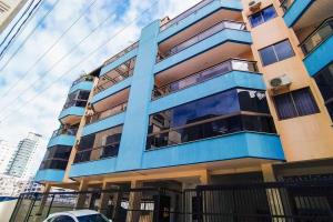 un edificio azul con un coche aparcado delante de él en Apto Meia Praia/Itapema en Itapema