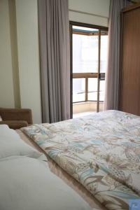 a bedroom with a bed and a window with a view at Apto Meia Praia/Itapema in Itapema