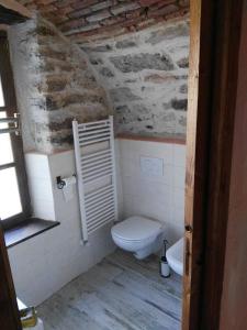 La salle de bains est pourvue de toilettes blanches et d'un mur en briques. dans l'établissement Casale La Selva Cottege piccolo, à Piano Porlezza