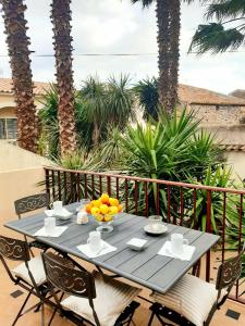 een tafel met een schaal sinaasappels op een balkon met palmbomen bij Le Médicis - Centre village calme in Bessan