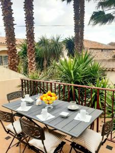 a table with a bowl of oranges on a balcony with palm trees at Le Médicis - Centre village calme in Bessan