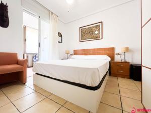a bedroom with a large white bed and a chair at Lindo al Mar con Piscina/Tenis in Benicàssim