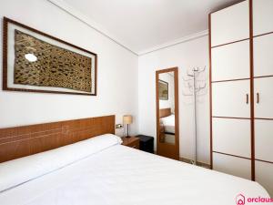 ein weißes Schlafzimmer mit einem Bett und einem Spiegel in der Unterkunft Lindo al Mar con Piscina/Tenis in Benicàssim