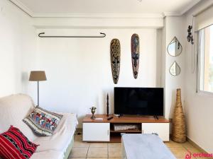 - un salon avec une télévision et un canapé dans l'établissement Lindo al Mar con Piscina/Tenis, à Benicàssim