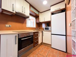 eine Küche mit weißen Schränken und einem Kühlschrank in der Unterkunft Lindo al Mar con Piscina/Tenis in Benicàssim + 48 Fotos