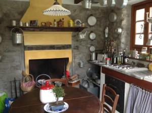 een keuken met een tafel en een open haard bij Casale La Selva Cottege grande in Piano Porlezza